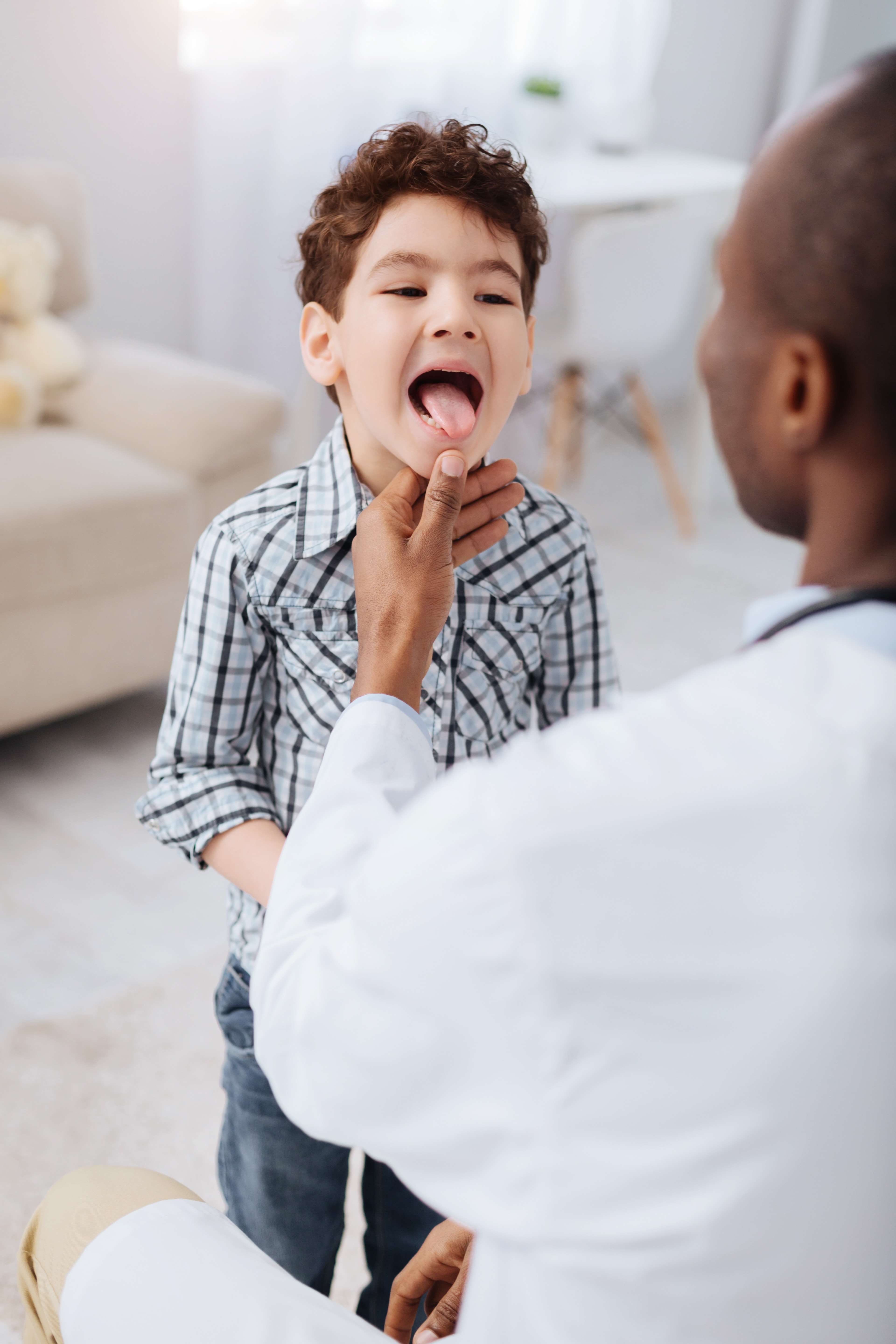 Doctor examining young boy's throat in medical office
