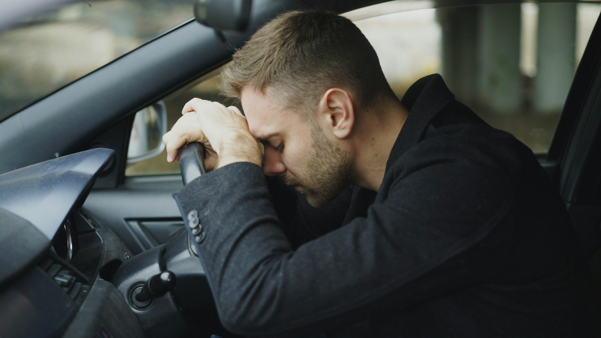 man with head on steering wheel