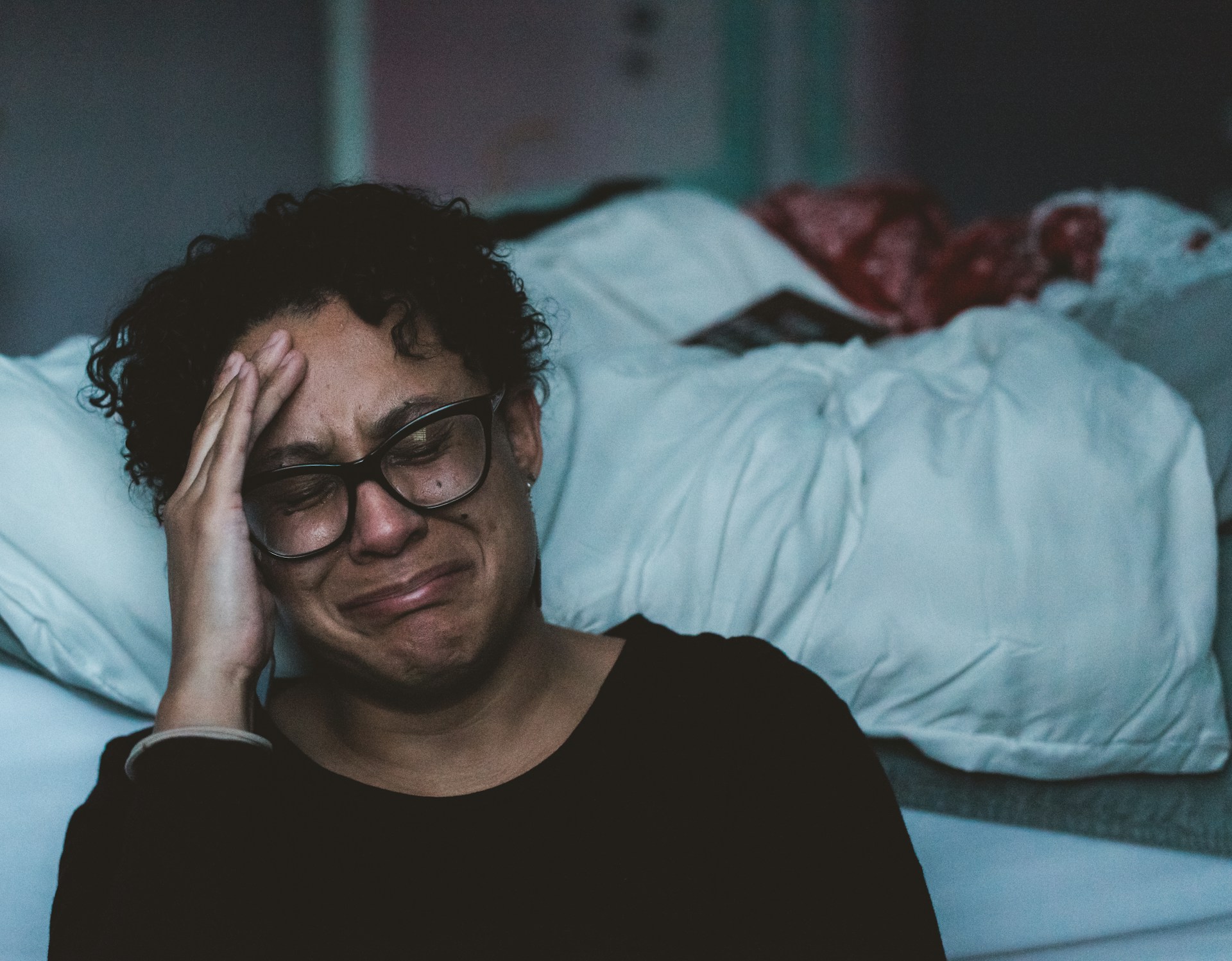 woman crying next to bed