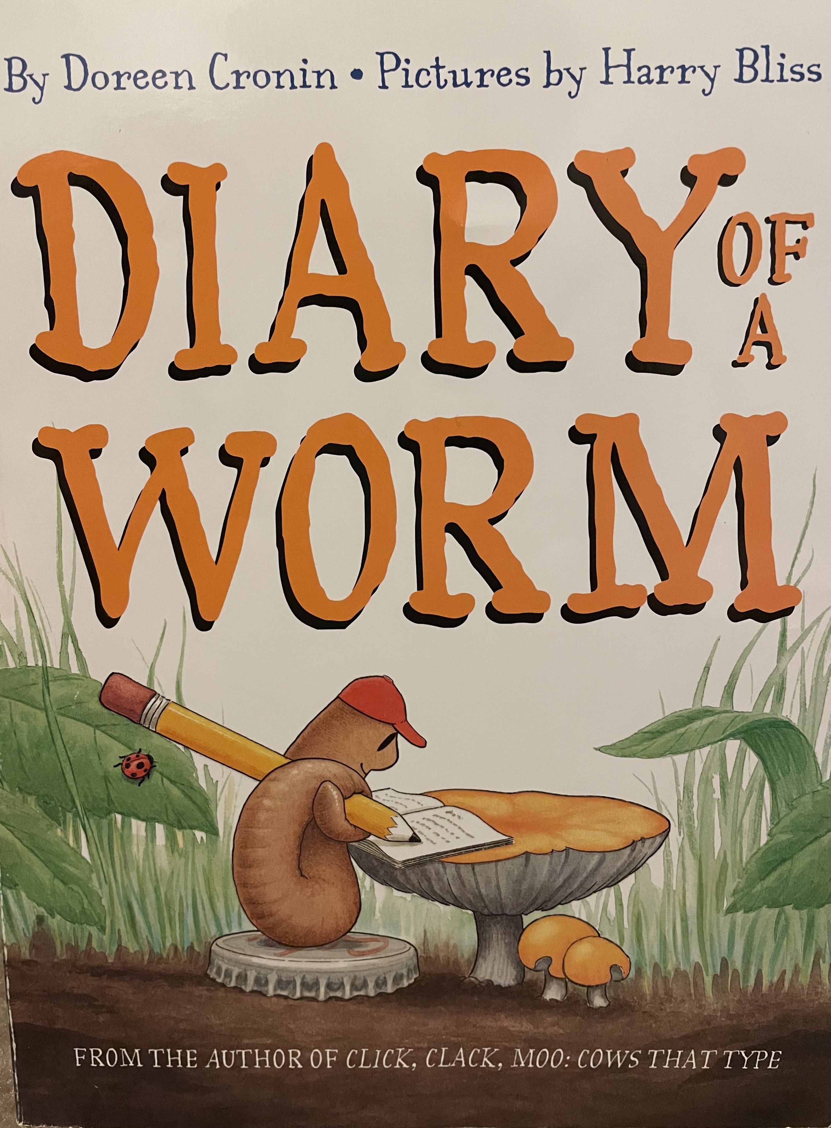 Diary of a Worm book cover with an illustrated worm writing at a desk surrounded by grass and