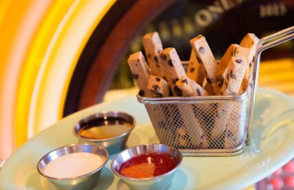 Chocolate chip cookie fries in a wire basket with dipping sauces