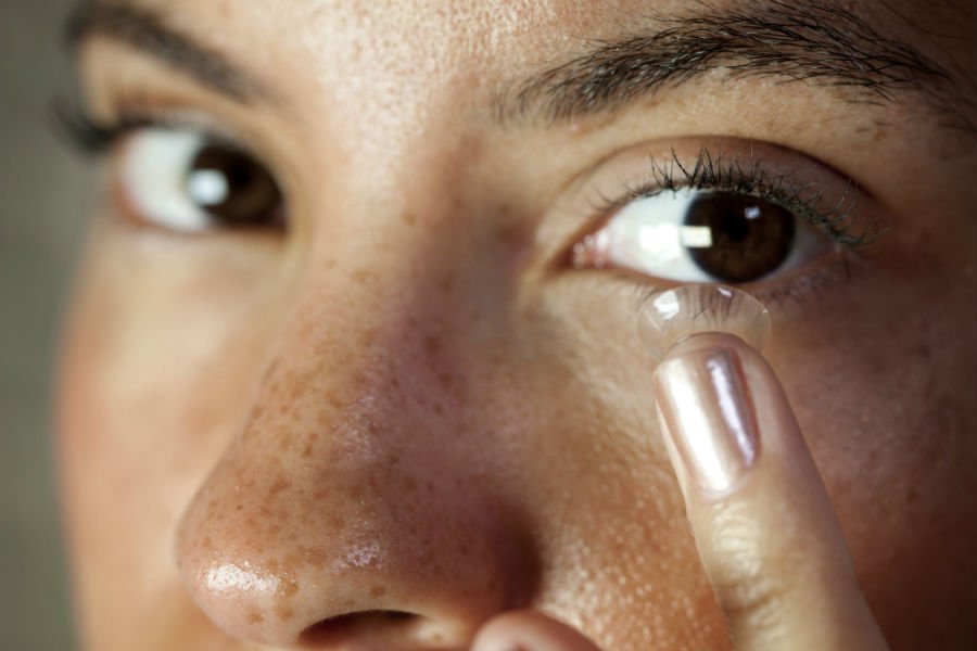 woman applying contacts 5 Healthy Makeup Habits For Contact Lens Wearers 1