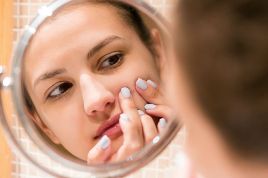 woman picking pimple acne myths