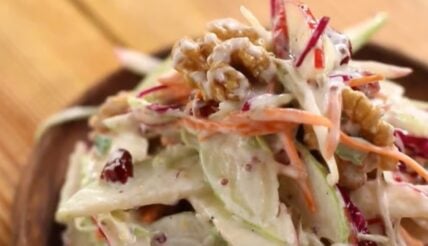 Apple walnut salad with shredded cabbage and carrots on a wooden surface