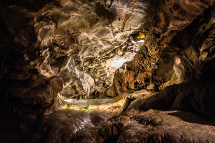 Interior of a cave with layered rock formations and natural light filtering through an opening