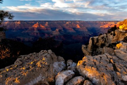 Golden hour light illuminates the Grand Canyon's layered rock formations and distant plateaus