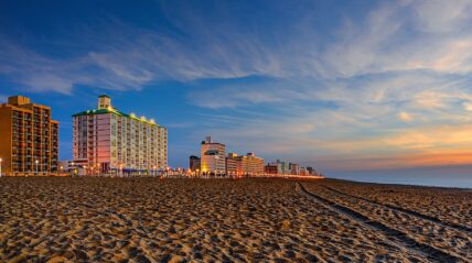 Virginia Beach oceanfront hotels and high-rise buildings at sunset with sandy beach in foreground