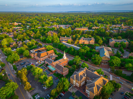 Aerial view of historic Williamsburg colonial town surrounded by dense forest and waterfront