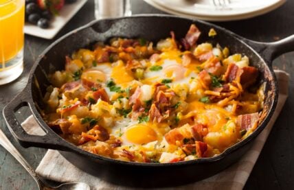 Bacon and egg breakfast skillet with diced potatoes and green garnish