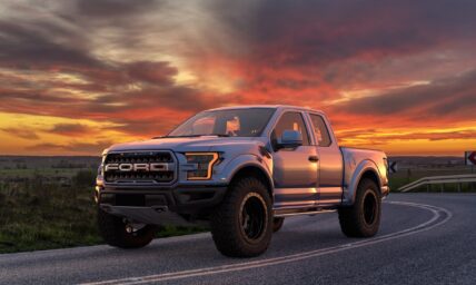 Ford F-150 pickup truck parked on a highway at sunset with dramatic orange sky