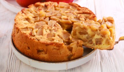 Homemade apple cake with sliced almonds on top, one slice removed