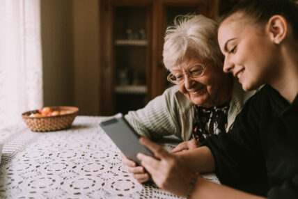 Grandmother and granddaughter looking at a tablet together at a kitchen table