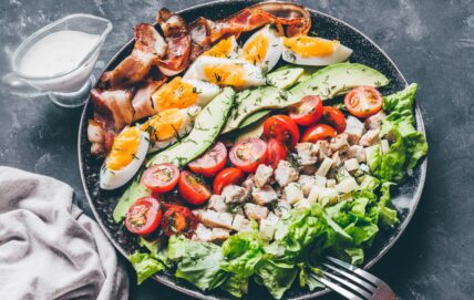 Classic Cobb salad with bacon, eggs, avocado, tomato, and diced chicken on lettuce
