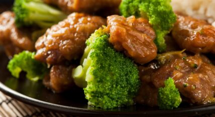 Beef and broccoli stir-fry with glossy brown sauce on a dark plate
